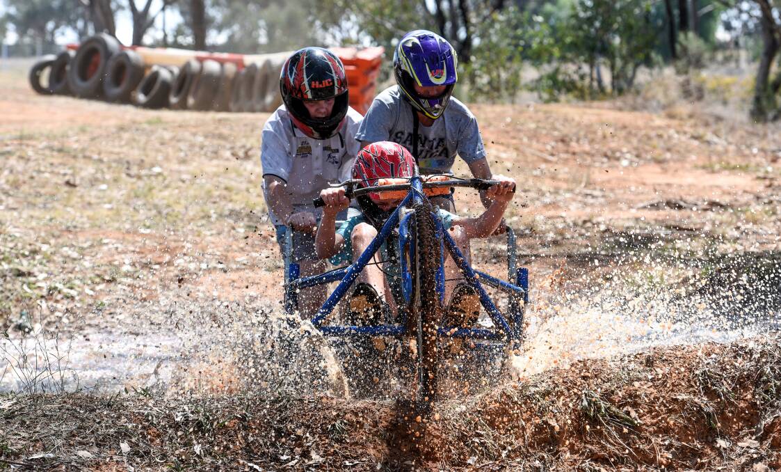 MAKING A SPLASH: Year 9 students Ethan McDonald and Angus Murray give Archie Cudmore a push into the mud at the annual Calrossy billy cart derby which drew 150 entrants. Photo: Gareth Gardner 220917GGD01 