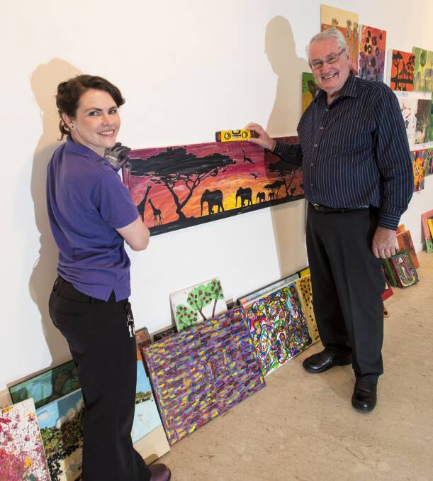 UP ON SHOW: Kate Armstrong and Challenge CEO Barry Murphy hang the artworks on show at Ray Walsh House. 211116PHB18