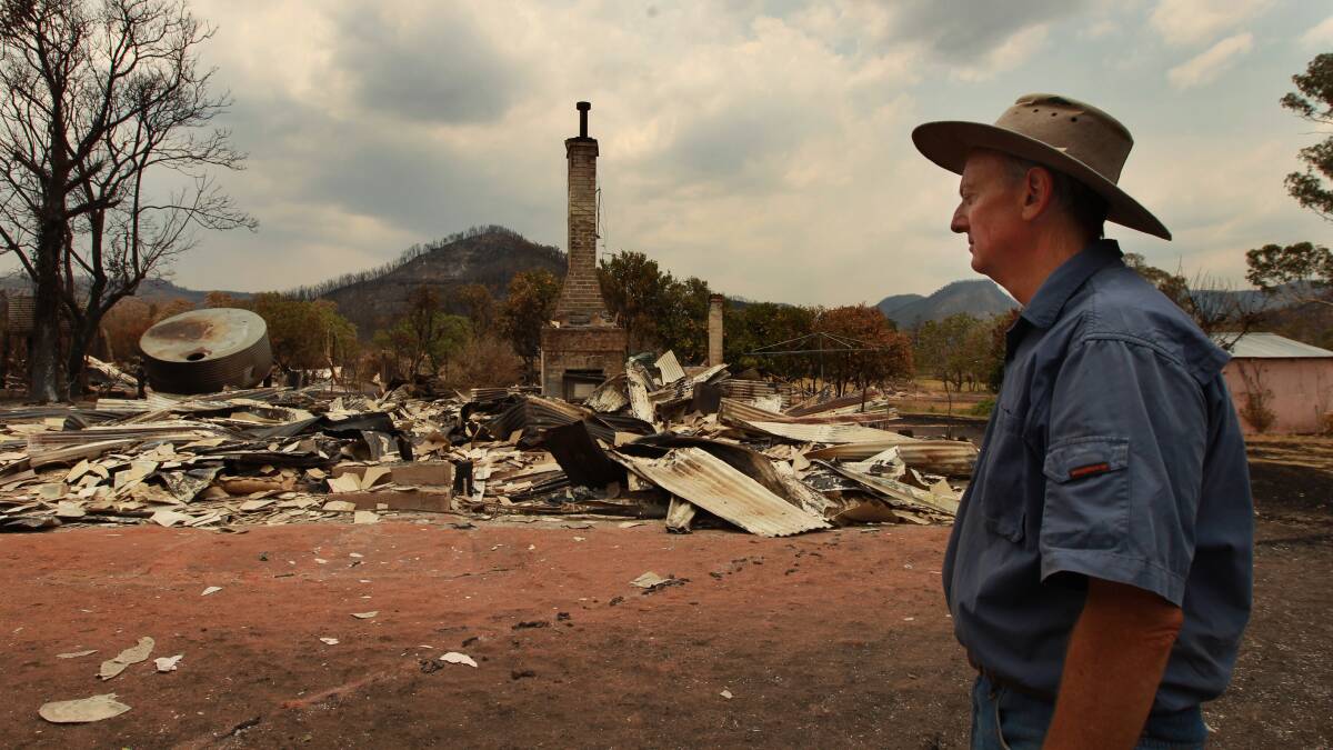Vincent Morrissey surveys the damage in front of what used to be his home in Timor Road, Coonabarabran. The fire front now extends for 158 kilometres. Photo: JACKY GHOSSEIN
