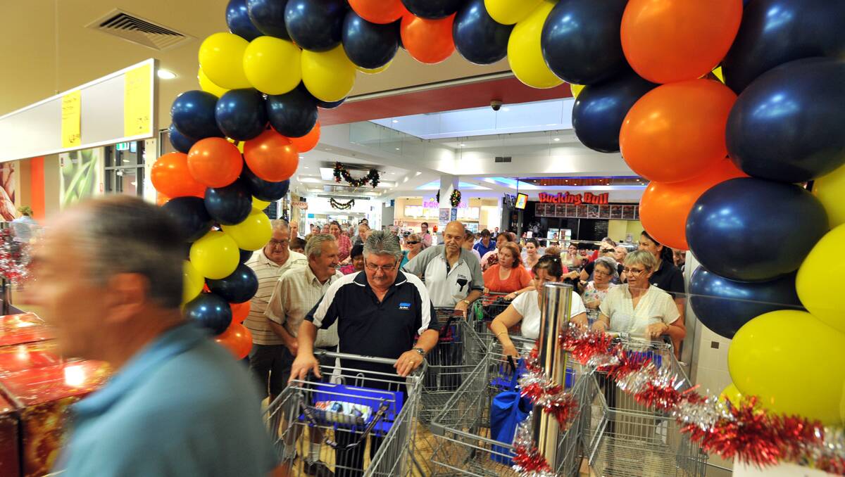 FIRST THROUGH: The first shoppers head through the balloon arch. Photo: Barry Smith 281112BSA10