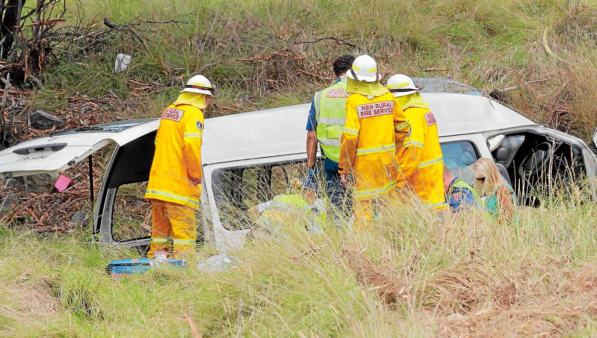 Emergency service  workers attend to the injured in a mini-van  accident on the New England Highway. 