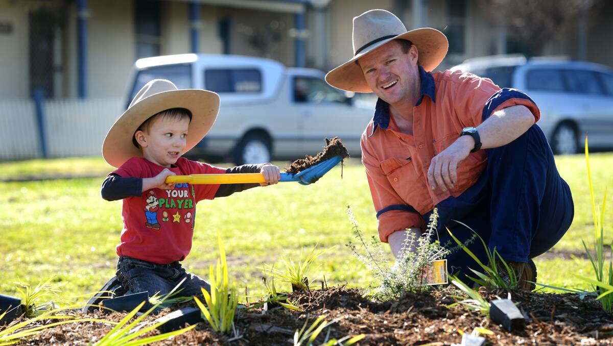 LEFT – AT WORK AND PLAY: Bailey,4, and his dad, Scotty Miller, help with the tree planting at Burgess Park,  North Tamworth, yesterday. Scotty said Bailey helped plant trees for 15 minutes then jumped on the new swing set for 20 minutes. Photo: Barry Smith 280713BSA04