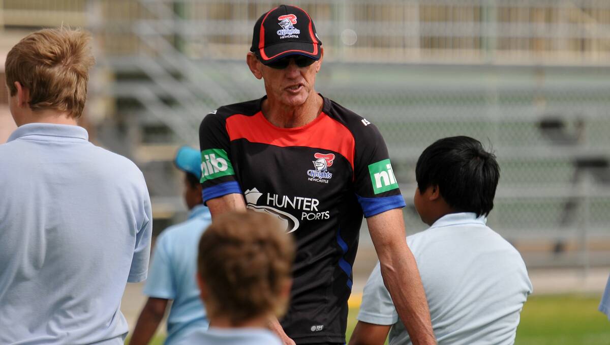 HOW IT’S DONE: Wayne Bennett shows some Tamworth High School kids the correct way to pass a football  yesterday at Scully Park. 220213GRA13