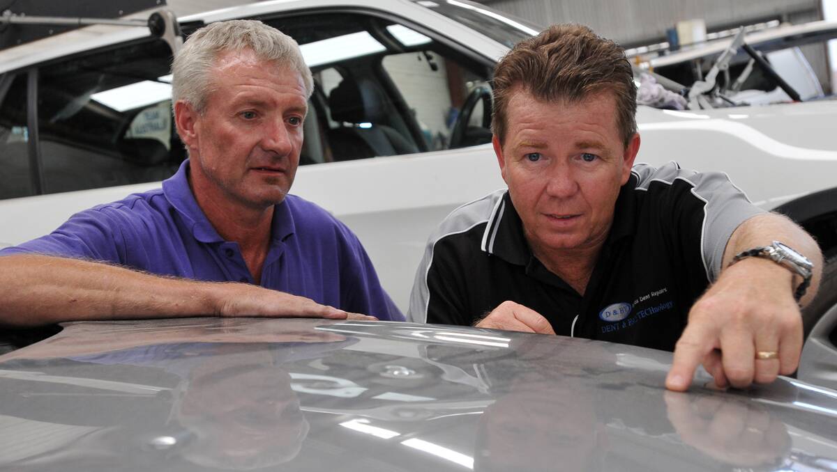 MORE TO DO: From left, Stephen Pattison and Mark Stansfield inspect a  hail-damaged car at Taminda Smash Repairs. December’s violent storm is expected to create work for local panel beaters, glaziers, roofers and builders for up to 12 months. Photo: Geoff O’Neill 080113GOE01