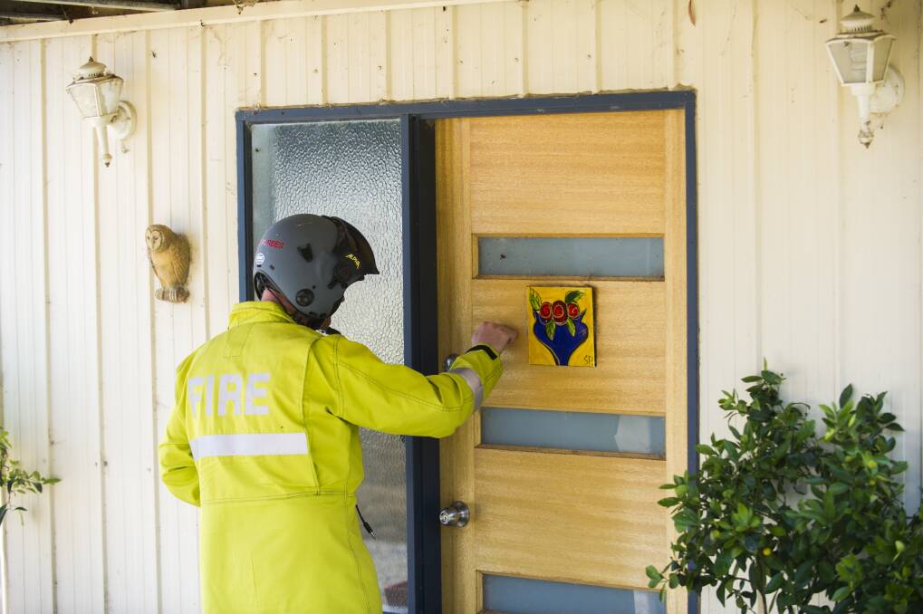 An RFS helicopter crew member knocks to return a borrowed repair tool to a home on Hazeldell Rd, near Bungendore on January 9, 2013. Photo: Rohan Thomson.