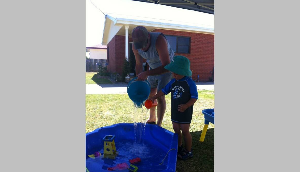 Peter Bonney helping his son Mitchell Bonney fill up the pool. Photo: Elizabeth Brandenburg/The Advocate